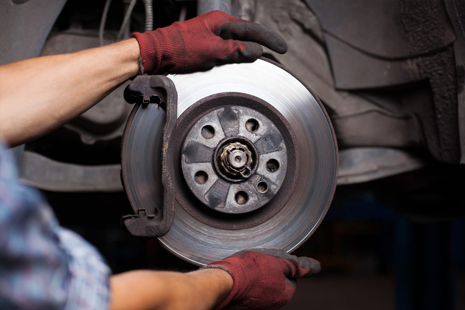 Mechanic holding a brake rotor during brake repair service, emphasizing vehicle maintenance and safety in Columbus, OH.
