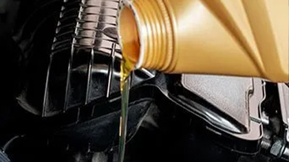 Oil pouring from a container into a vehicle's engine, highlighting the importance of oil and filter change for vehicle maintenance.