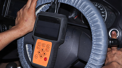 Hand using a diagnostic tool on a steering wheel, illustrating steering system repair and vehicle diagnostics.