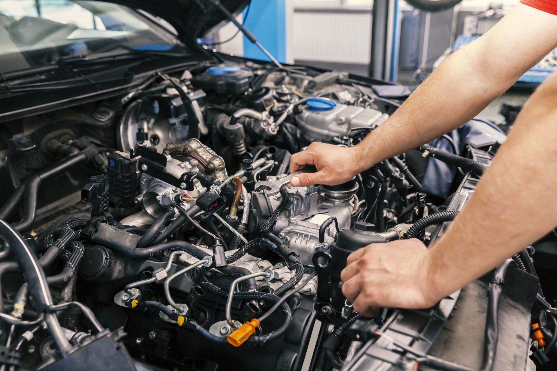 Mechanic performing engine repair in an auto shop, focusing on intricate components and electrical systems of a vehicle's engine.